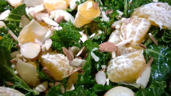 Simply dressed kale with olive oil and flaky sea salt, topped with orange segments and almonds